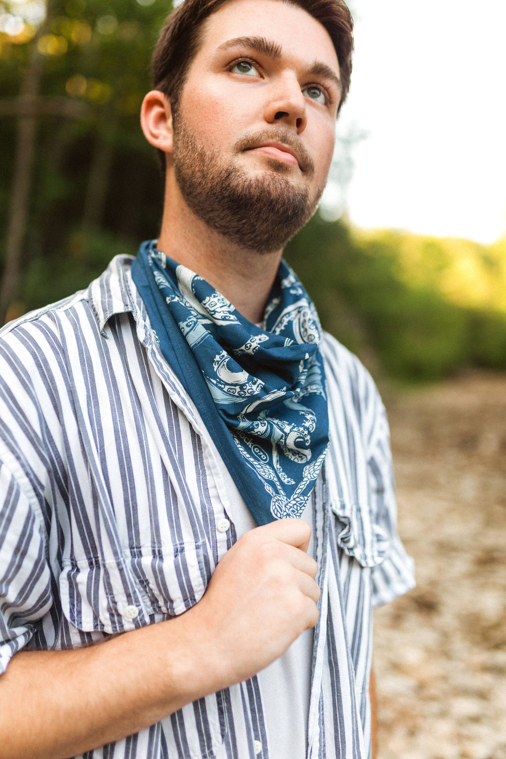 The individual wearing a blue bandana outdoors with a blurred natural background