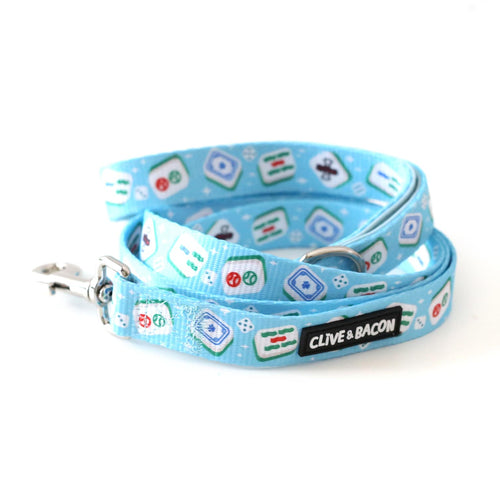 A bright blue dog leash with a repeating mahjong tile pattern, featuring a black brand label that reads 'CLIVE & BACON' and a silver metal clasp, photographed on a white background.