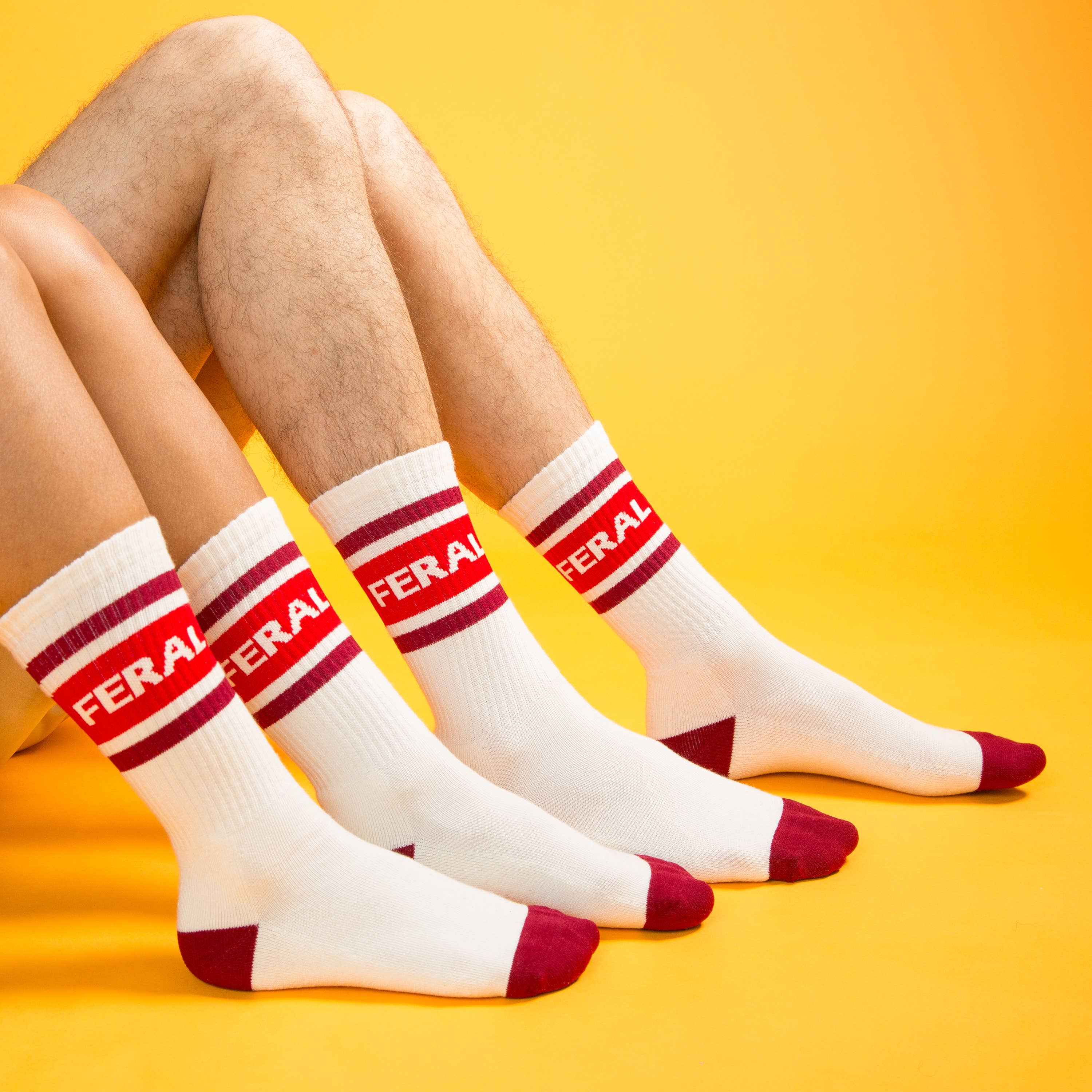 White socks with red accents and 'FERAL' branding on a yellow background