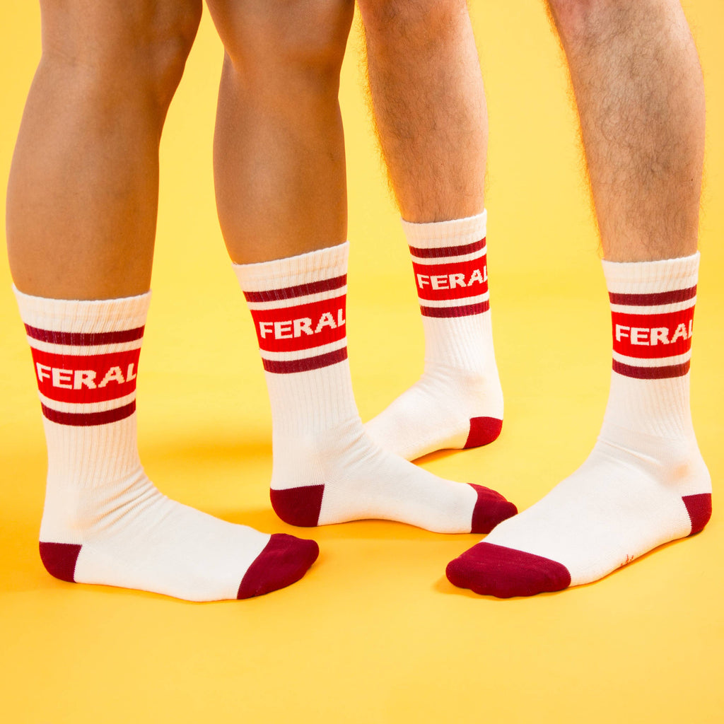 White socks with red accents and 'FERAL' branding on a yellow background